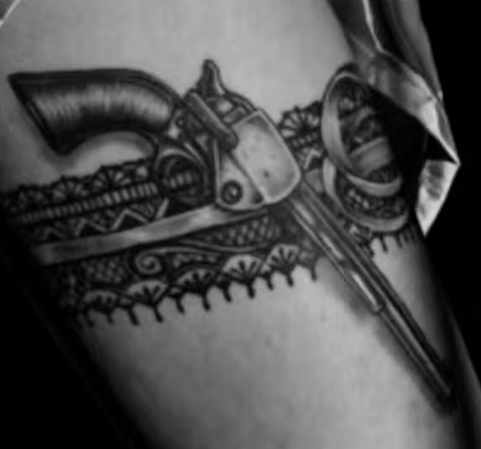 Black and grey tattoo of a revolver tucked into a detailed lace garter design, inked at Old Stone Tattoo House in Athlone, Ireland