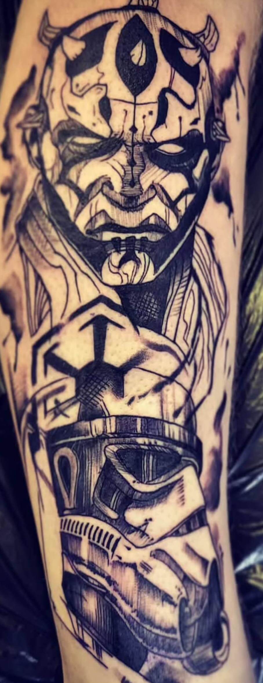 Black and grey tattoo of Darth Maul holding a Stormtrooper helmet, featuring a sketch-style design with bold black lines, shading, and dynamic textures, tattooed at Old Stone Tattoo House in Athlone, Ireland.